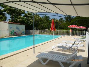 a pool with chairs and umbrellas next to a swimming pool at Camping Le Mouliat in Moncrabeau