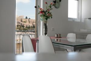 a dining room with a table and chairs and a vase with flowers at Mind-blowing Acropolis View Apt in Athens