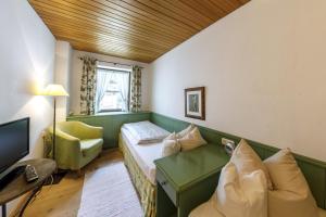 a room with a bed and a couch and a television at Hotel & Gasthof Fraundorfer in Garmisch-Partenkirchen