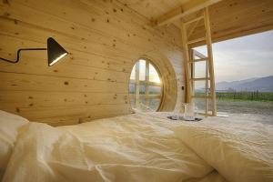 a bed in a wooden room with a window at Green Resort Glamping in Radlje ob Dravi