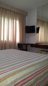 Hotel Ipanema Inn Higienópolis في ساو باولو: غرفة فندقية بسرير وتلفزيون بشاشة مسطحة