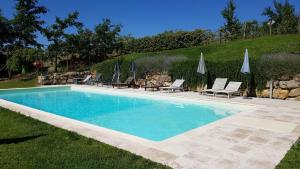 a swimming pool with chairs and umbrellas in a yard at Appartamento I 2 Archi in Siena