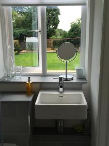 a bathroom sink with a mirror and a window at The Garage in Banbury