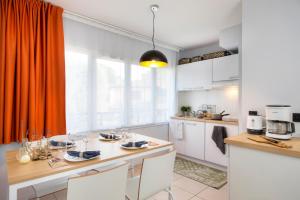 a kitchen with an orange curtain and a table and chairs at Privilège Appart-Hôtel Domaine De Mai - parking gratuit in Mougins