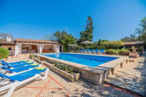 a pool with lounge chairs and a house at Can Giro in Pollença