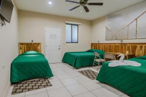 a room with two green beds and a table at Hotel Los Chilamates in Granada