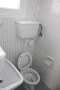 a white bathroom with a toilet and a sink at Sanoudos in Naxos Chora