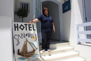 una mujer de pie en las escaleras de una casa con una señal en Sanoudos, en Naxos Chora