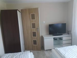 a room with two beds and a television and a cabinet at Pokoje u Ewy in Piotrowice