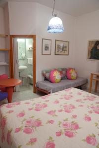 una camera con letto e divano con cuscini rosa di Hotel Il Falchetto a Pontedera