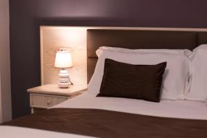 a bed with a black pillow and a lamp on a night stand at Hotel Soleluna in Piano di Sorrento