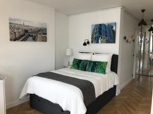 a white bedroom with a large bed with green pillows at Appartement Seine et Marais in Paris