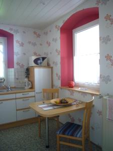 uma cozinha com paredes cor-de-rosa, uma mesa e uma janela em Ferienwohnung im alten Schulhaus - keine Monteure em Plech