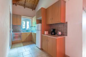 cocina con armarios de madera y nevera blanca en Navarone Villas, en Petrochori