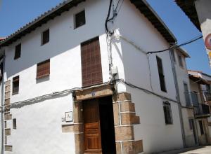 un antiguo edificio blanco con puerta de madera en Apartamentos Rurales Víctor Chamorro del Arco, en Hervás