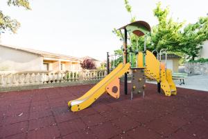 un parque infantil con un tobogán amarillo y un banco en Logis Hotel Restaurant La Porte des Cévennes en Anduze