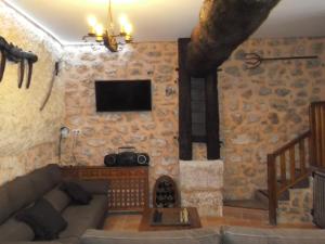 sala de estar con sofá y TV en la pared en Las tercias de Curiel, en Curiel de Duero