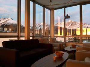 a room with a couch and tables and snow covered mountains at Vila Polar in Štrbské Pleso