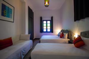 um quarto com duas camas e um sofá e uma janela em Hôtel Fontaine Campini em Fez
