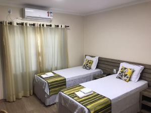 a room with two beds and a air conditioner at Open Hotel in Telêmaco Borba