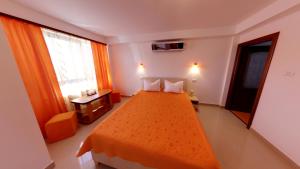 a bedroom with a large bed with an orange blanket at Pensiunea Casa Beatrice in 2 Mai