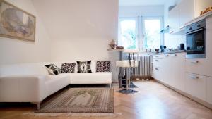 a living room with a white couch and a kitchen at Ekatarina Apartments in Baden-Baden