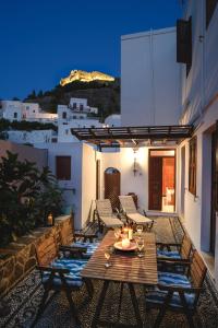 una mesa de madera y sillas en un patio por la noche en Thea Villas and Suite, en Lindos