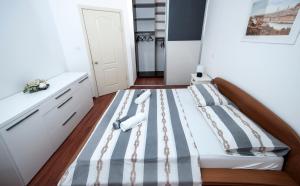 a small bedroom with a bed with striped sheets at Žnjan Beach Apartments in Split