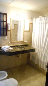 y baño con lavabo, espejo y aseo. en La Posada de Akasha en Villa General Belgrano
