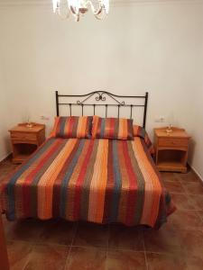 a bed with a striped comforter and two night stands at Casa Flor in Punta Mujeres