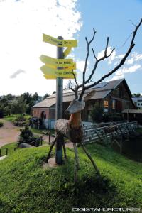 a statue of a woman with a hat next to a street sign at Gîte à La Montagne in Labaroche