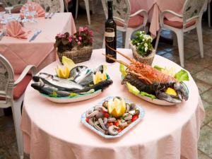 una mesa con platos de comida y una botella de vino en Hotel Giardino Delle Ninfe E La Fenice, en Isquia