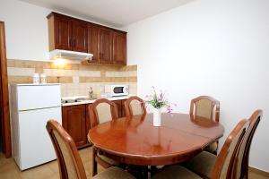 a kitchen with a wooden table and a white refrigerator at Apartmani More in Sveti Stefan
