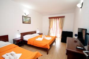 a hotel room with two beds and a flat screen tv at Apartmani More in Sveti Stefan