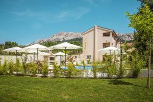 un complexe avec une piscine, des parasols et un bâtiment dans l'établissement Residence Mediterraneo, à Baška
