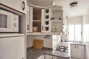 Una cocina con gabinetes blancos y un refrigerador blanco. en Apartamento Jardines Vía Parque, en Alicante