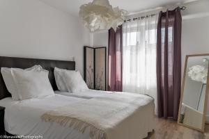 a bedroom with a bed with white sheets and a chandelier at La Roseraie du Lac in Annecy