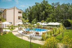 a pool with chairs and umbrellas in a yard at Residence Mediterraneo II in Baška