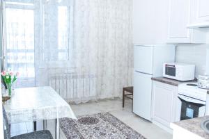 uma cozinha branca com uma mesa e um micro-ondas em Luxury apartment Promenade Expo em Astana