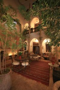 una sala de estar con mesas, sillas y árboles en Riad Mur Akush, en Marrakech