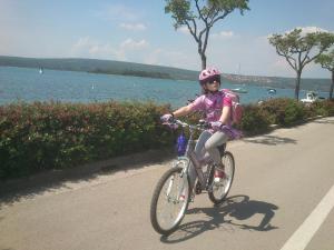 a young girl riding a bike down a road at Garden Apartment Braut in Kornić