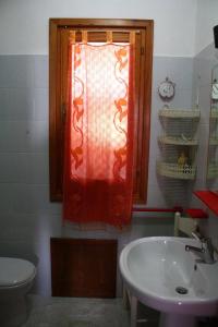 バデージにあるbilocale fantastica vista mareのバスルーム(赤いカーテンと洗面台付きの窓付)