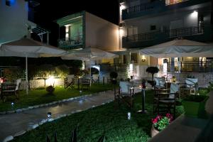 an outdoor patio with tables and umbrellas at night at Arion Hotel in Skala Potamias