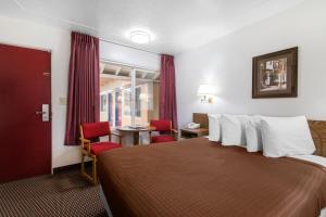 um quarto de hotel com uma cama grande e cadeiras vermelhas em Eureka Town House Motel - Historic Old Town em Eureka