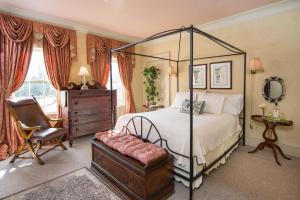 a bedroom with a canopy bed and a chair at Captain Farris House in South Yarmouth
