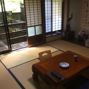 a room with a table and chairs and windows at Oogi Onsen Oogiso in Minamioguni