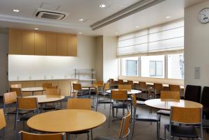 an empty classroom with tables and chairs and a clock at Hotel Frontier Iwaki in Iwaki