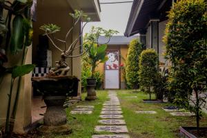 een tuin met een loopbrug met planten en een deur bij Nyoman Guesthouse Berawa Canggu in Canggu
