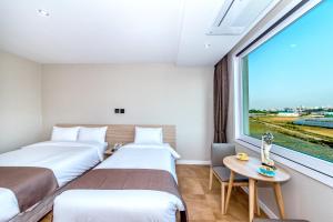 Duas camas num quarto com uma janela grande em Jeju In Hotel em Jeju