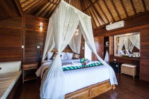 ein Schlafzimmer mit einem weißen Bett mit Baldachin in der Unterkunft The Cubang Hut's Lembongan in Nusa Lembongan